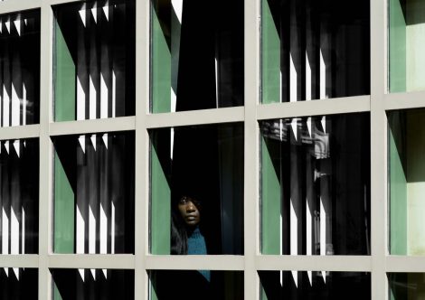 A woman peeking through a patterned window.