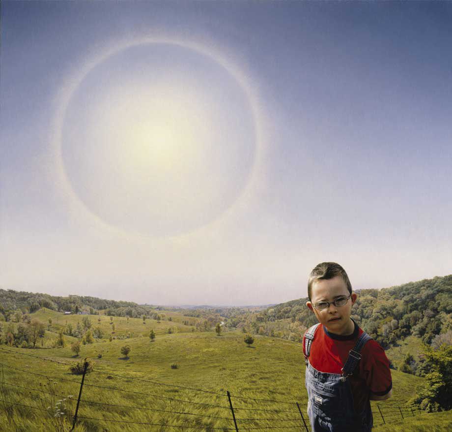 A young boy standing next to a field with the sun shining