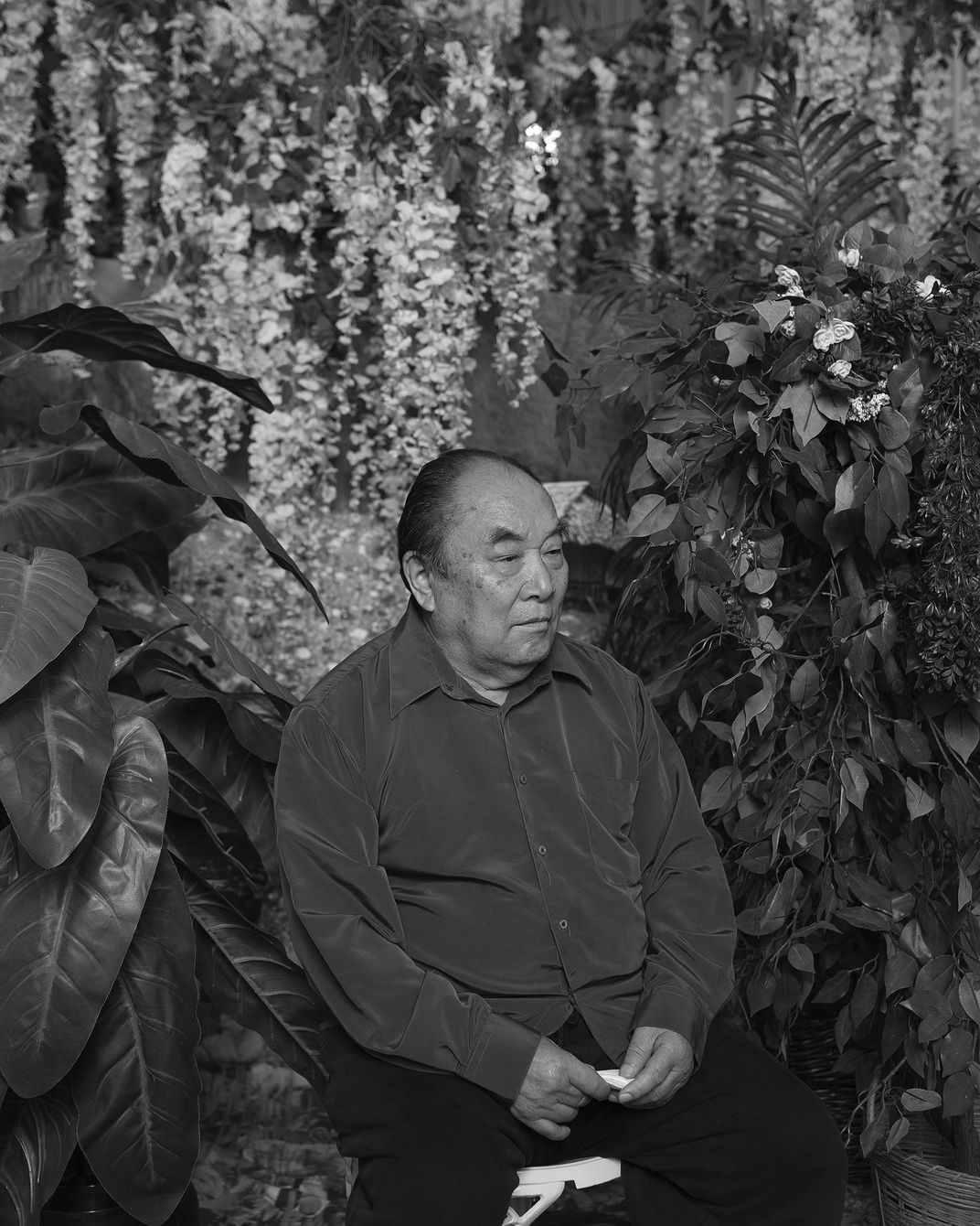 Black and white portrait photo of a man sitting on a stool