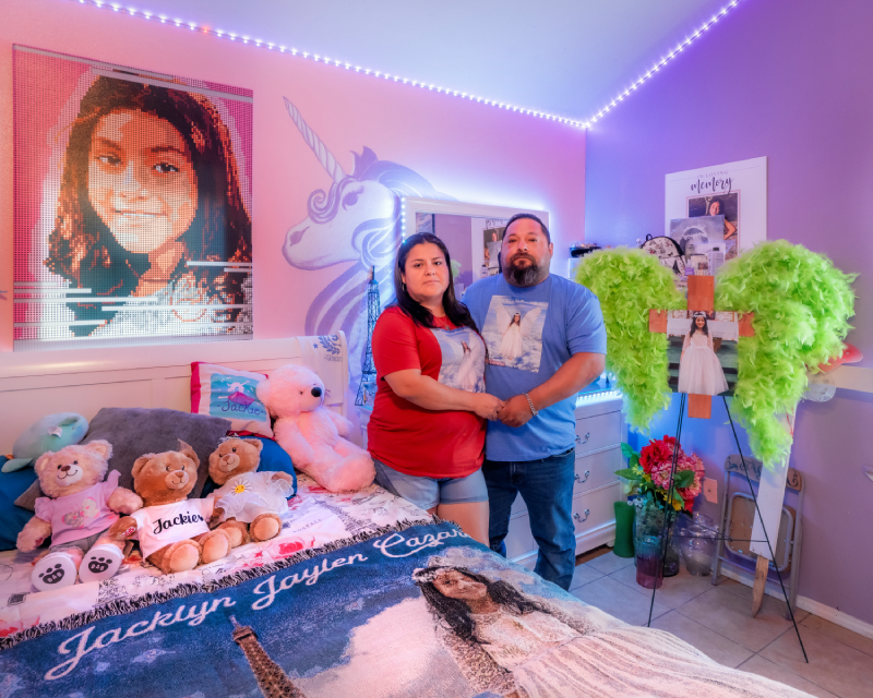 A man and woman standing in child's room surrounded by items reminding them of the child